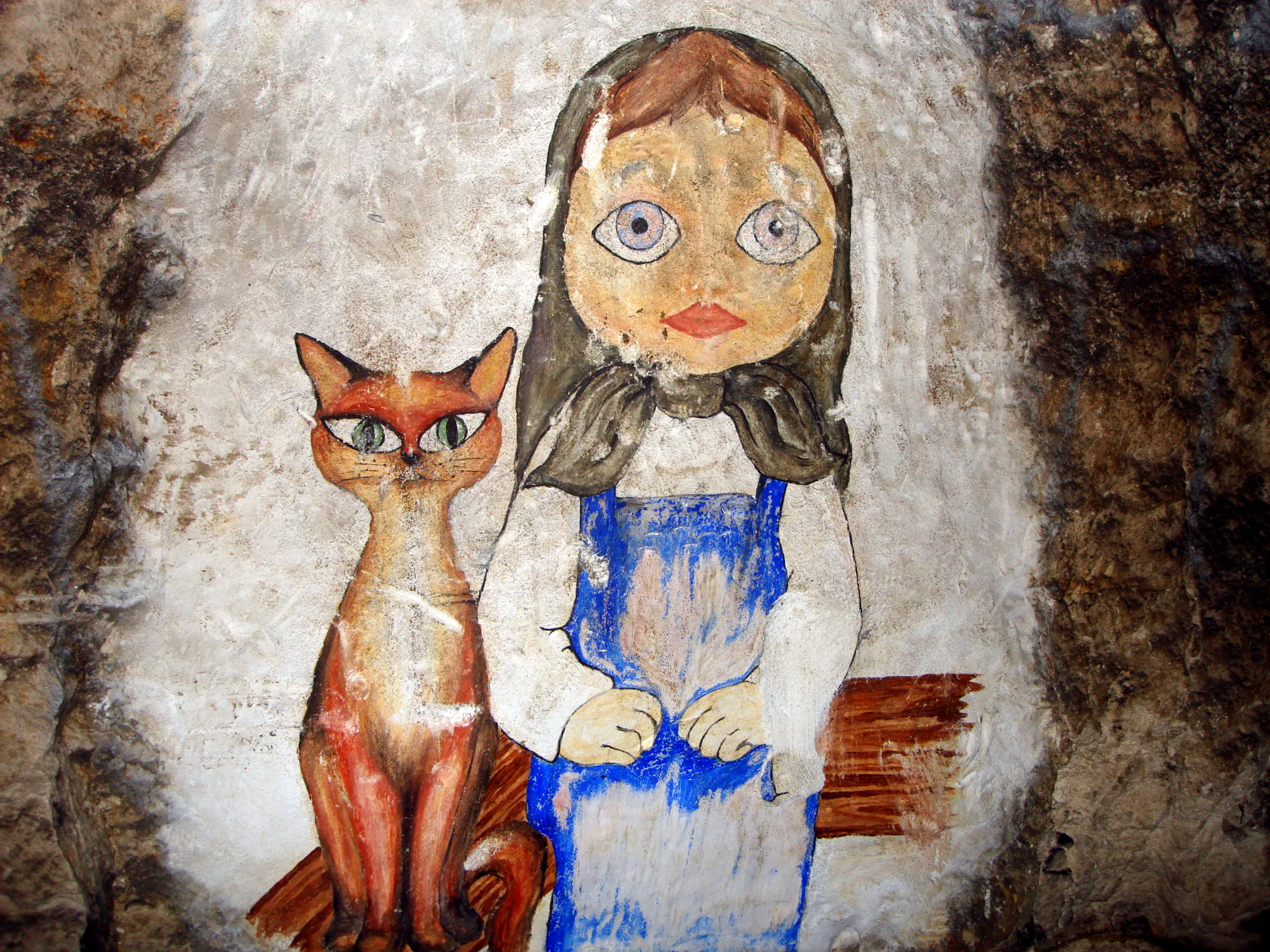 Фреска на каменной стене: девочка с большими глазами в синем переднике и белом платке сидит рядом с рыжим котом с зелёными глазами.