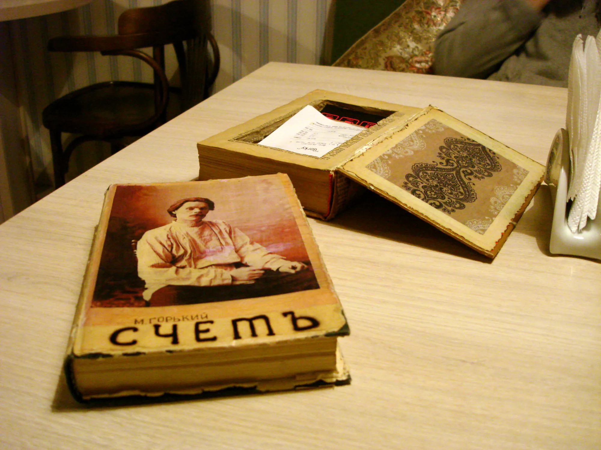 Старая книга М. Горького «Счетъ» с портретом автора на обложке лежит на столе рядом с раскрытой книгой и чеком.