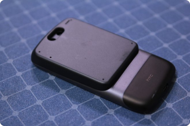 Смартфон HTC с отсоединённой задней крышкой, лежащий на синей сетчатой поверхности; виден логотип HTC на батарее.