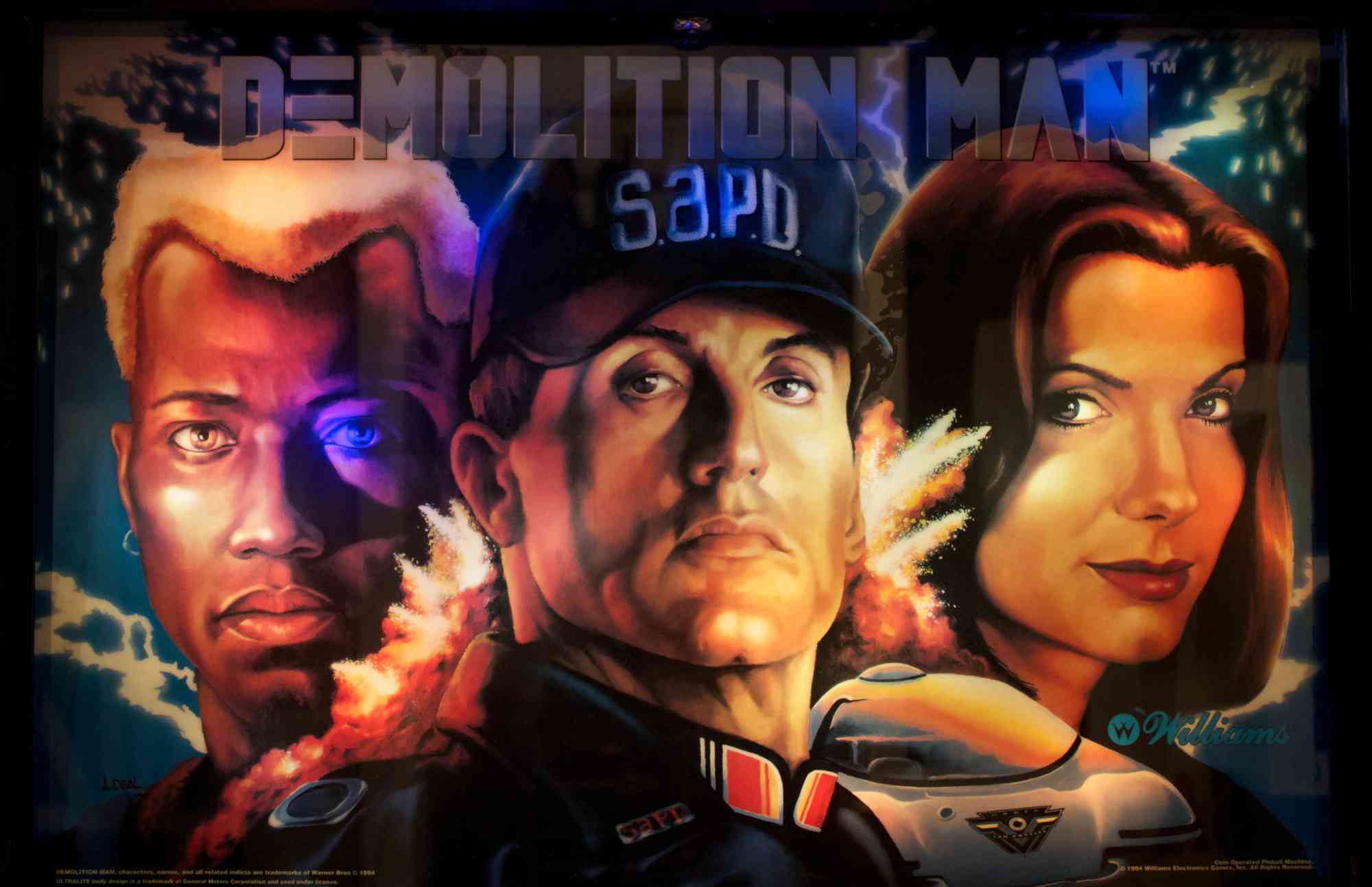 Постер аркадной игры Demolition Man с портретами трёх персонажей: мужчины в кепке S.A.P.D., блондина и брюнетки, на фоне взрывов и неба; логотип Williams в углу.