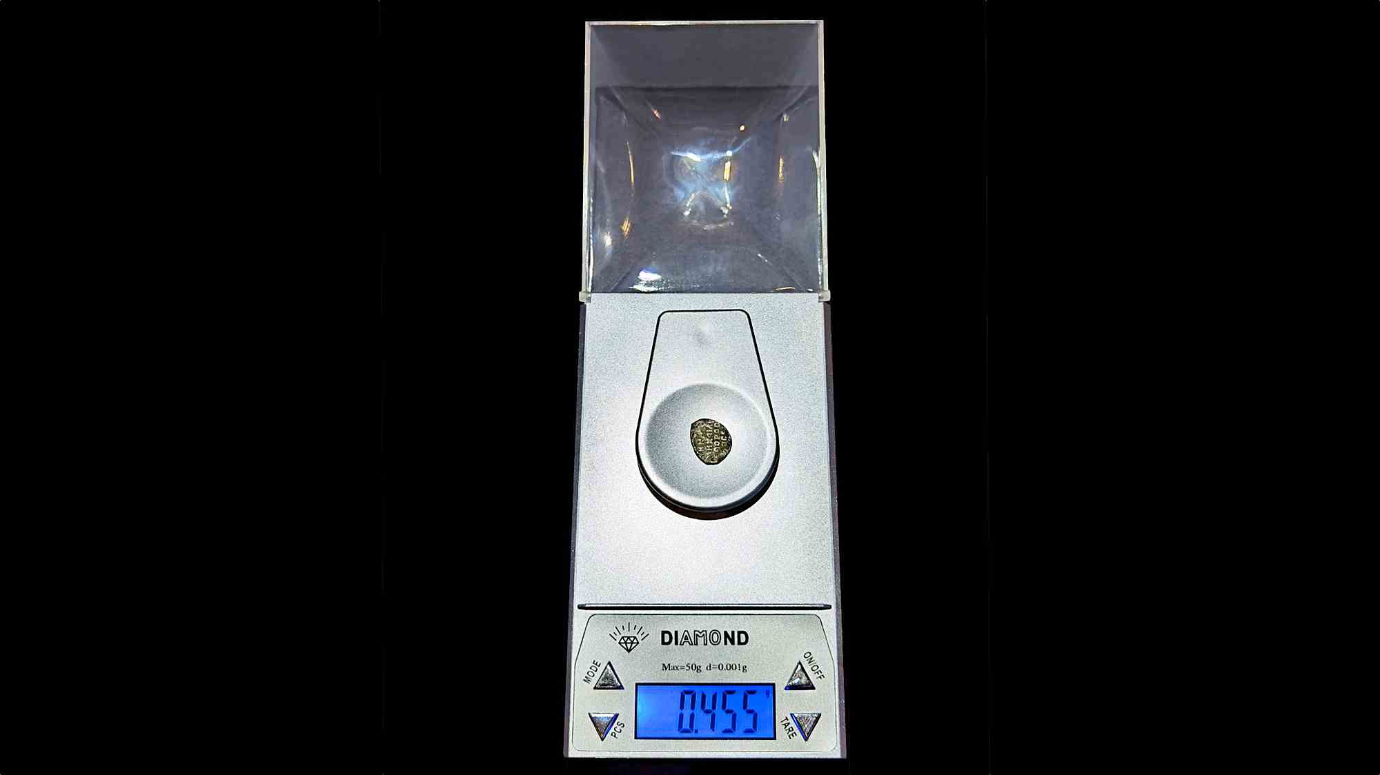 Цифровые весы Diamond с прозрачным колпаком, на чаше лежит монета, на синем дисплее отображается вес 0.455 г.