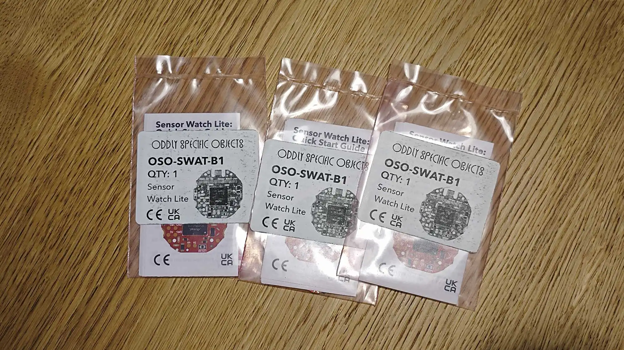 Три прозрачных пакета с платами датчиков OSO-SWAT-B1 от Oddly Specific Objects, на этикетках указано: Sensor Watch Lite, количество 1, знаки CE и UKCA.