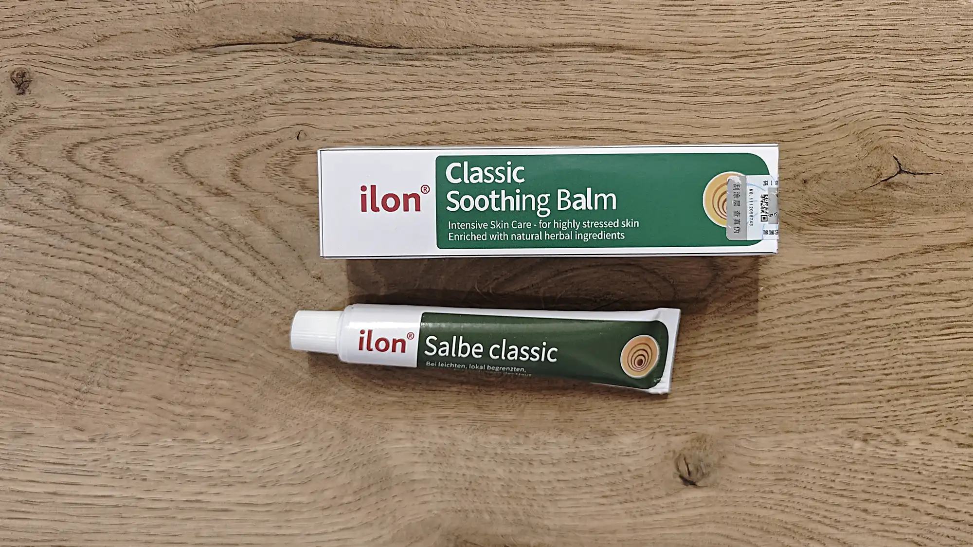Коробка и тюбик мази ilon Classic Soothing Balm (Salbe classic) с надписью «Intensive Skin Care - for highly stressed skin» на деревянном фоне.