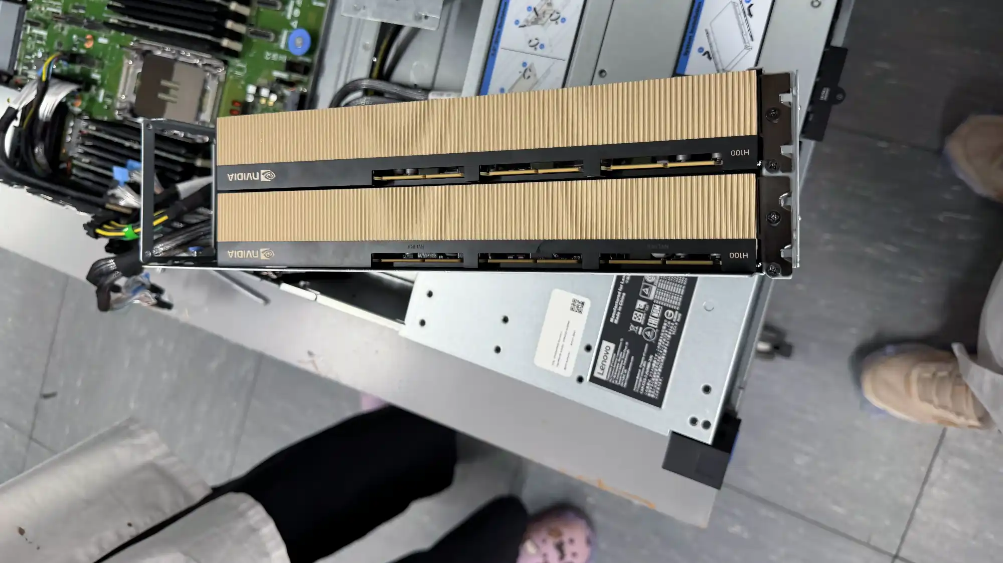 Два золотистых серверных модуля NVIDIA H100, установленных в серверную стойку Lenovo, с видимыми разъёмами и маркировкой на корпусе.