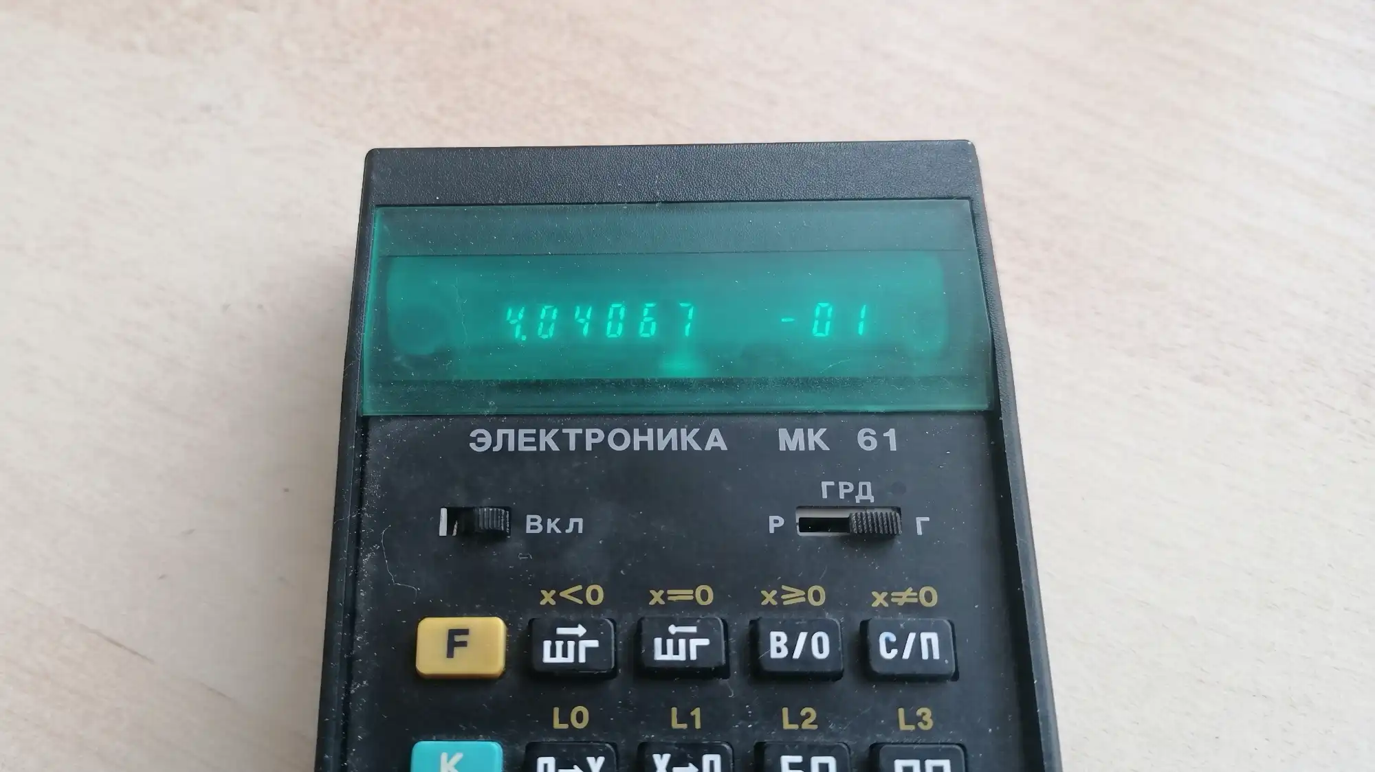 На дисплее калькулятора «ЭЛЕКТРОНИКА МК 61» отображается число 4.04067 -01, видны переключатели «Вкл», «ГРД» и кнопки с обозначениями функций.